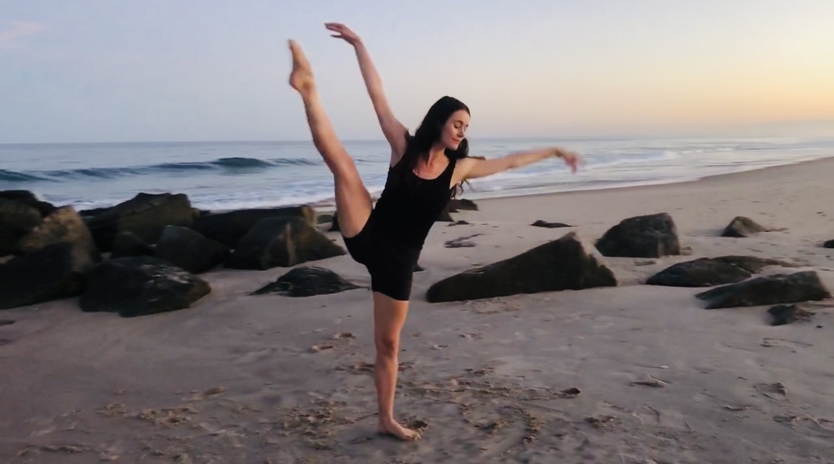 Sherah doing a ballet arabesque on the beach at sunset